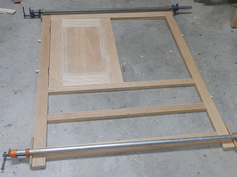 photo of the rails, stiles and one of the raised panel door components used to build the armoire frame assembly front section dry fitted to show the location of the door hinges