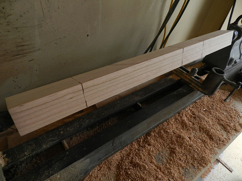 photo of 1-3/4" x 1-3/4" counter stool leg secured between lathe centers with scribed and cut sections to be turned and gouged