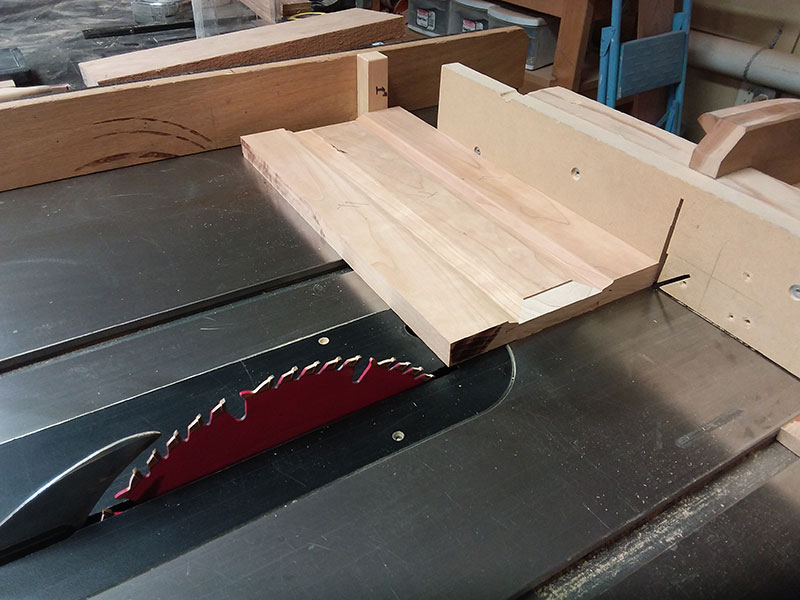 photo of trimming the rails and center panel used to build the bedside table frame side sections to length in the table saw